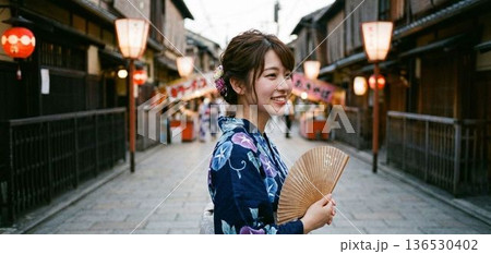 京都・祇園の街角で夕涼みをする浴衣姿の女性 136530402