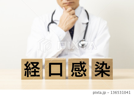 「経口感染」と書かれたブロックと悩む医師 136531041