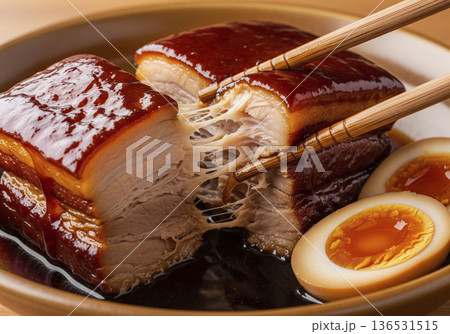 箸でほぐれるほど柔らかく煮込まれた豚の角煮と煮卵 136531515