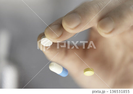 服用前の白い錠剤を指でつまむクローズアップ 服用前の白い錠剤を指でつまむクローズアップ 136531855