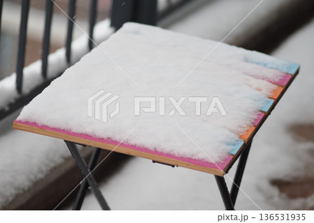 Snow covers a table on a balcony in winter weather 136531935