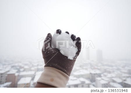 Snowball in hand during winter in city 136531948