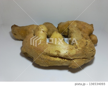 Fresh Ginger Root on White Surface Close-up of a fresh ginger root placed on a clean white surface with a plain white background. The ginger features a rough, tan-colored skin with knobby protrusions Fresh Ginger Root on White Surface Close-up of a fresh ginger root placed on a clean white surface with a plain white background. The ginger features a rough, tan-colored skin with knobby protrusions 136534093