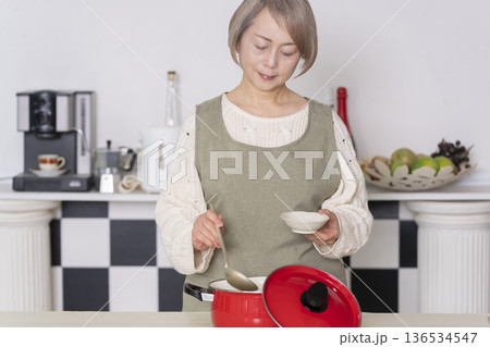 キッチンで作った料理の味見をするシニア女性 136534547