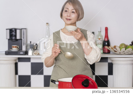 キッチンで作った料理の味見をするシニア女性 キッチンで作った料理の味見をするシニア女性 136534556