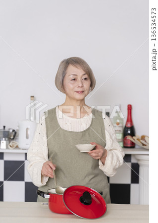キッチンで作った料理の味見をするシニア女性 キッチンで作った料理の味見をするシニア女性 136534573