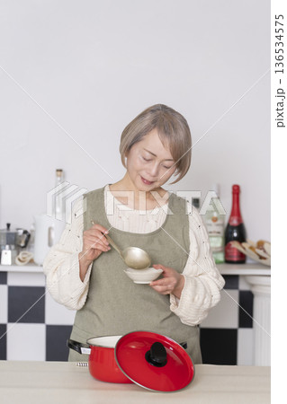 キッチンで作った料理の味見をするシニア女性 キッチンで作った料理の味見をするシニア女性 136534575