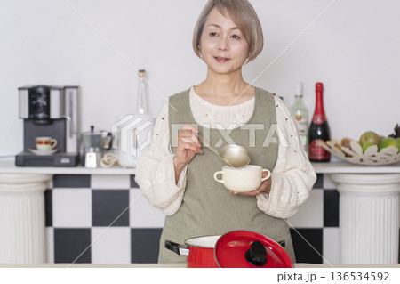キッチンで作った料理の味見をするシニア女性 キッチンで作った料理の味見をするシニア女性 136534592