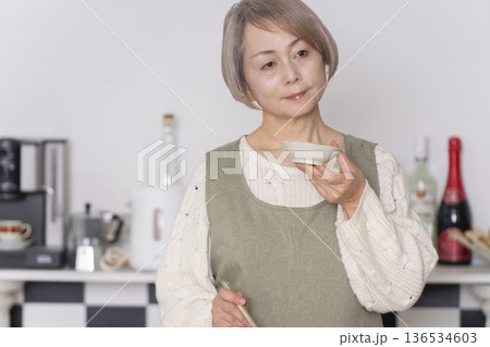 キッチンで作った料理の味見をするシニア女性 キッチンで作った料理の味見をするシニア女性 136534603