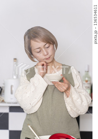 キッチンで作った料理の味見をするシニア女性 キッチンで作った料理の味見をするシニア女性 136534611