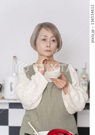 キッチンで作った料理の味見をするシニア女性 キッチンで作った料理の味見をするシニア女性 136534612