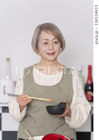 キッチンで作った料理の味見をするシニア女性 キッチンで作った料理の味見をするシニア女性 136534615