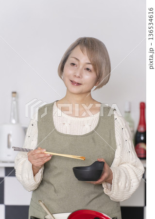 キッチンで作った料理の味見をするシニア女性 キッチンで作った料理の味見をするシニア女性 136534616