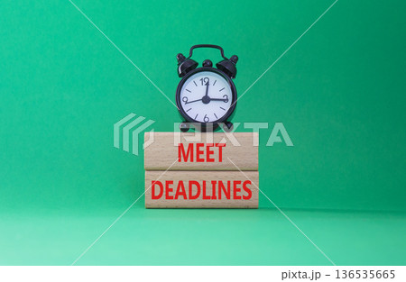 Meet Deadlines symbol. Concept word Meet Deadlines on wooden blocks. Beautiful green background with alarm clock. Business and Meet Deadlines concept. Copy space 136535665