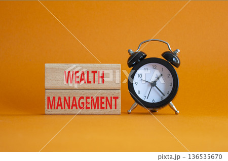 Wealth Management symbol. Concept words Wealth Management on wooden blocks. Beautiful orange background with alarm clock. Business and Wealth Management concept. Copy space 136535670