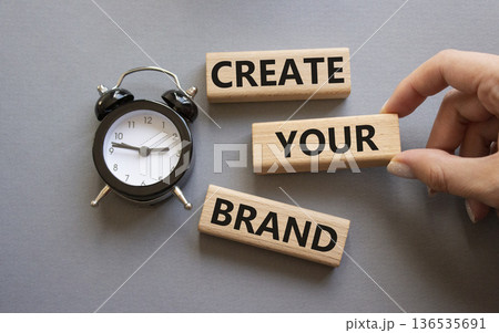 Brand symbol. Concept words Create your Brand on wooden blocks. Businessman hand. Beautiful grey background with alarm clock. Business and Create your Brand concept. Copy space. Brand symbol. Concept words Create your Brand on wooden blocks. Businessman hand. Beautiful grey background with alarm clock. Business and Create your Brand concept. Copy space. 136535691