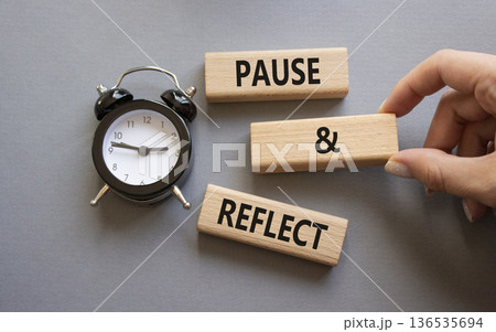 Pause and Reflect symbol. Concept words Pause and Reflect on wooden blocks. Businessman hand. Beautiful grey background with alarm clock. Business and Pause and Reflect concept. Copy space. 136535694