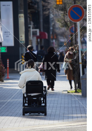 冬の昼の都市の街で歩く人々と車椅子を乗る若い女性の姿 冬の昼の都市の街で歩く人々と車椅子を乗る若い女性の姿 136535955