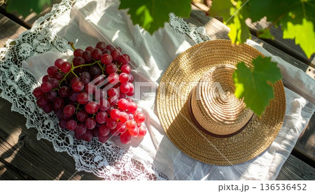 Red Grapes with Straw Hat on Rustic Wooden Table 136536452