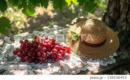 Red Grapes with Straw Hat on Rustic Wooden Table 136536453