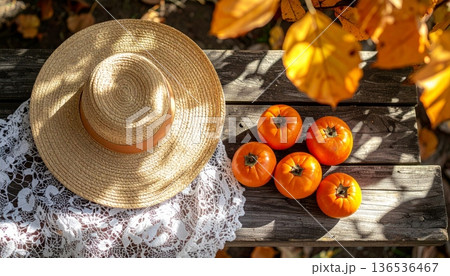 Persimmon with Straw Hat on Rustic Wooden Table in Autumn 136536467