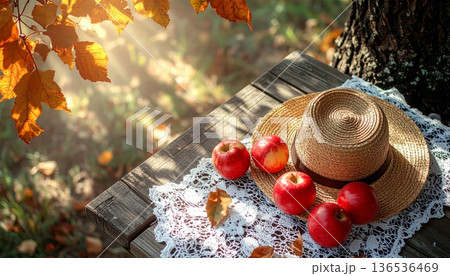 Red Apple with Straw Hat on Rustic Wooden Table in Autumn 136536469