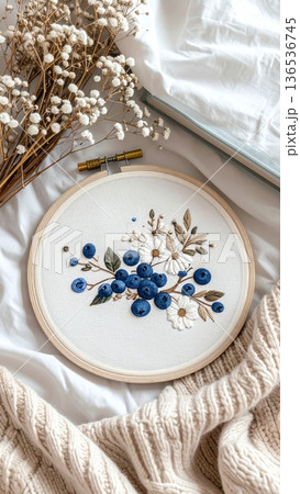 Embroidered Blueberry Hoop on Bed with Knitted Blanket Book and White Dried Flowers 136536745