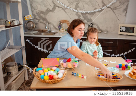 Mother and daughter make crafts and decorations together for the Easter spring holiday. Family sitting at the table 136539919