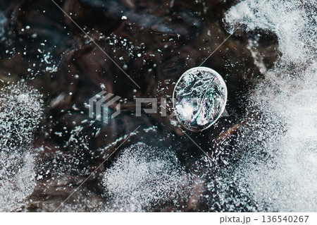 湖に張った氷に閉じ込められた虹色に輝く気泡 136540267