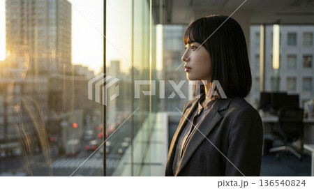 オフィスの窓際で夕日を浴びて景色を眺める日本人女性の横顔 136540824