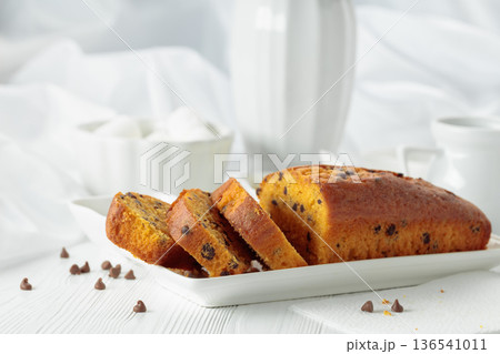 Cake with chocolate pieces on a white table. Cake with chocolate pieces on a white table. 136541011