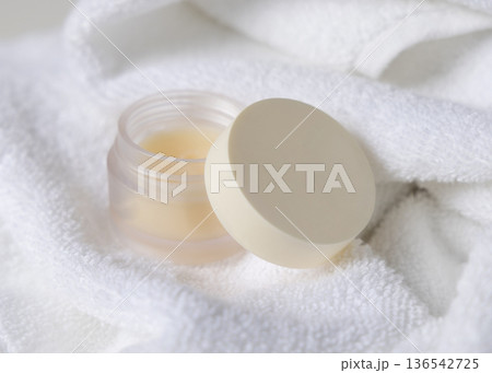 Mockup of lip balm jar with blank lid on white towel, top view. Unbranded cosmetic packaging Mockup of lip balm jar with blank lid on white towel, top view. Unbranded cosmetic packaging 136542725