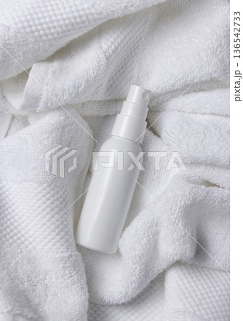 Mockup of white blank spray cosmetic bottle on white bath terry towel for spa hotel use 136542733