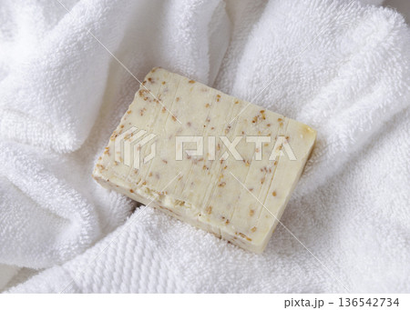 Unbranded beige solid soap bar on white terry towel top view, bathroom spa amenities 136542734