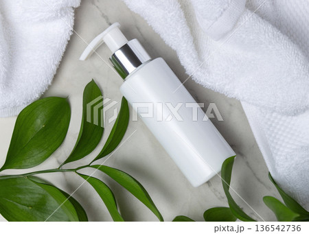 Mockup of blank white pump bottle near white bath terry towel and green leaves. Unbranded cosmetic Mockup of blank white pump bottle near white bath terry towel and green leaves. Unbranded cosmetic 136542736
