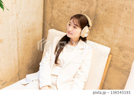カフェのソファーに座りヘッドホンで音楽を聴く女性 カフェのソファーに座りヘッドホンで音楽を聴く女性 136543191