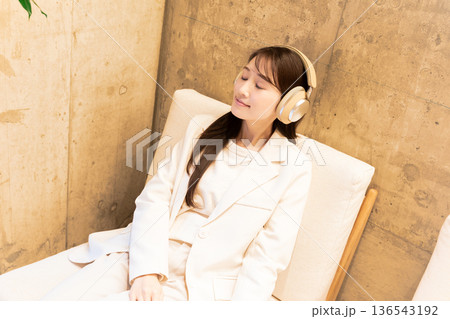 カフェのソファーに座りヘッドホンで音楽を聴く女性 カフェのソファーに座りヘッドホンで音楽を聴く女性 136543192