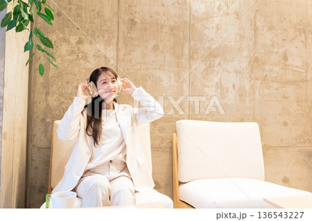 カフェのソファーに座りヘッドホンで音楽を聴く女性 カフェのソファーに座りヘッドホンで音楽を聴く女性 136543227