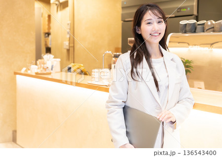 カフェでパソコンを持って立っている若い女性 カフェでパソコンを持って立っている若い女性 136543400