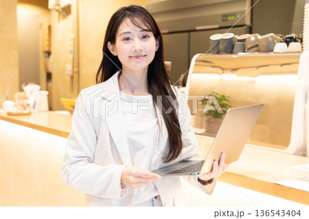 カフェでパソコンを持って立っている若い女性 136543404