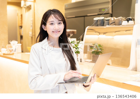 カフェでパソコンを持って立っている若い女性 カフェでパソコンを持って立っている若い女性 136543406