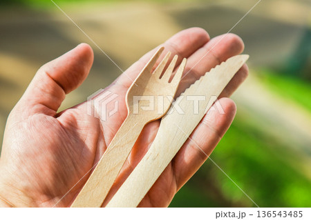 A pair of wooden cutlery fork and knife in hand on bokeh nature background 136543485