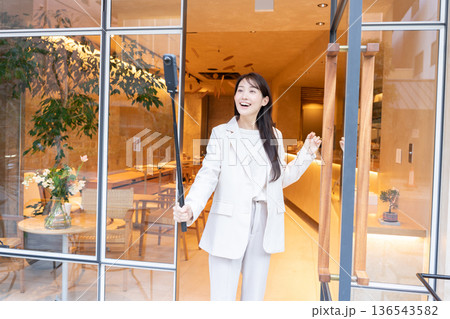 カフェの入り口で360度カメラで動画配信している若い女性 136543582