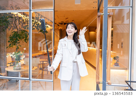 カフェの入り口で360度カメラで動画配信している若い女性 136543583