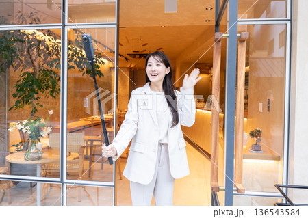 カフェの入り口で360度カメラで動画配信している若い女性 136543584