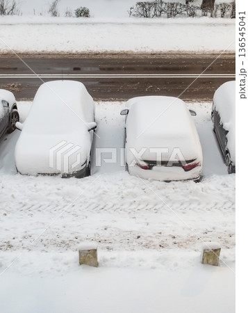 Cars covered with snow in a parking lot after a winter storm in an urban area 136545041