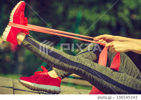 Girl doing exercise outdoor, using resistance fit band. Girl doing exercise outdoor, using resistance fit band. 136545343
