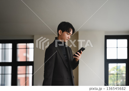 窓辺でスマホを見る男性 136545682