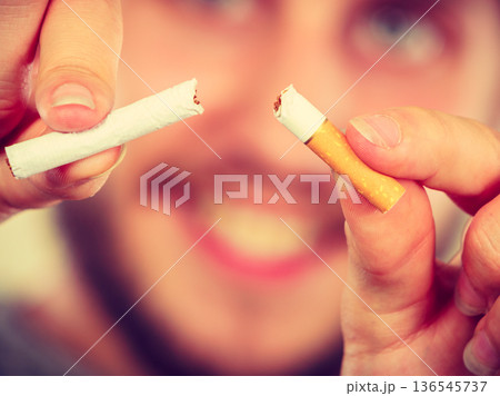 Smilling man is breaking a cigarette 136545737