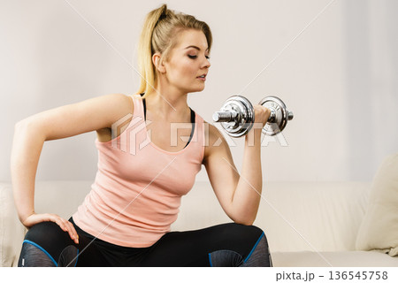 Woman working out at home with dumbbell Woman working out at home with dumbbell 136545758